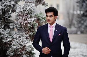 elegante modelo de hombre macho indio con traje y corbata rosa posado en el día de invierno. foto