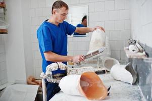 hombre protésico que hace prótesis de pierna mientras trabaja en laboratorio, hace un modelo de yeso. foto