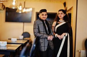 Lovely indian couple in love, wear at saree and elegant suit, posed on restaurant. photo