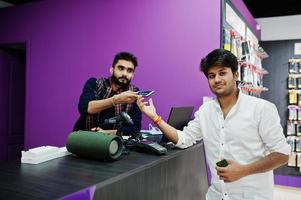 el comprador del cliente indio paga su nuevo teléfono inteligente para el vendedor con tarjeta de crédito en la tienda de teléfonos móviles. concepto de pueblos y tecnologías del sur de Asia. tienda de celulares foto