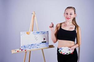 Beautiful woman artist painter with brushes and oil canvas posing in studio isolated on white. photo