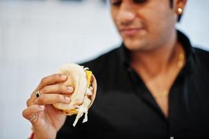 cierra la mano del hombre indio con una deliciosa hamburguesa. foto