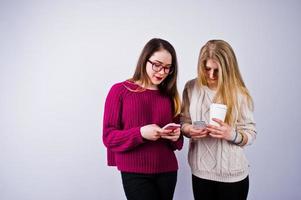 Two girls in purple dresses talking or texting on the phone in the studio. photo