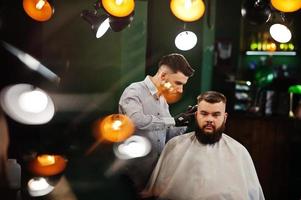 apuesto hombre barbudo en la barbería, peluquero en el trabajo. foto