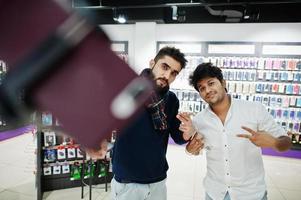 dos indios sirven al comprador del cliente en el teléfono móvil haciendo selfie con un palo monopie. concepto de pueblos y tecnologías del sur de Asia. tienda de celulares foto