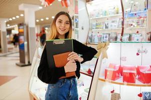 Portrait of young caucasian female woman seller stand with clipboard and notebook. Small business of candy souvenirs shop. photo