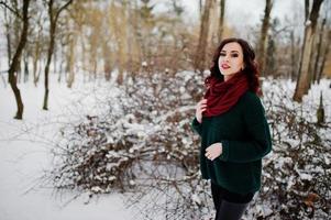 Brunette girl in green sweater and red scarf outdoor on evening winter day. photo