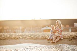 Mother and beautiful daughter having fun on the beach. Portrait of happy woman with cute little girl on vacation. photo