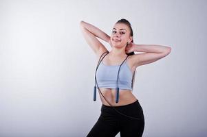 Cheerful attractive young fitness woman in top and black leggings with jump rope isolated over white background. photo