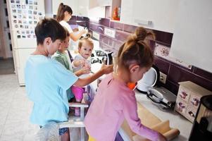 Mother with kids cooking at kitchen, happy children's moments. photo