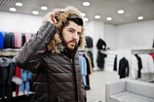 Stylish turkish man at the store of fur coats and leather jackets. Successful arabian beard man. photo