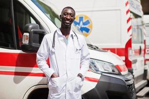 paramédico africano parado frente a un camión de ambulancia. foto