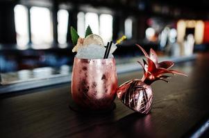 Alcoholic cocktail with ice in bronze glass on bar table. photo