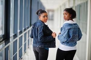 Two african woman friends in jeans jacket posed indoor together. photo