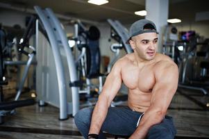 Fit and muscular arabian man doing workouts in gym. photo