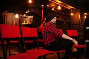 Indian man in checkered shirt and black turban sitting at bar. photo