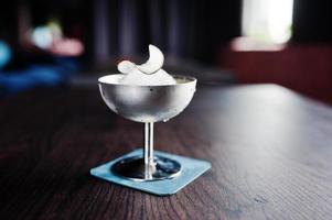 Alcoholic cocktail with ice and coconut in silver glass on bar table. photo