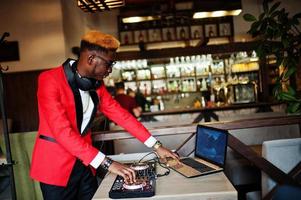 moda hombre afroamericano modelo dj en traje rojo con controlador de dj. foto