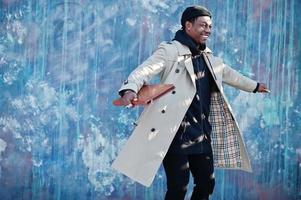 Handsome african american man posing outside in black hat and beige coat with folder in hand. photo