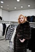 chica rubia de elegancia en abrigo de piel en la tienda de abrigos de piel y chaquetas de cuero. foto