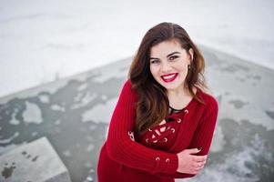 modelo morena de talla grande en rojo contra el lago congelado en el día de invierno. foto