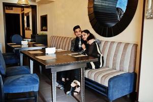 Lovely indian couple in love, wear at saree and elegant suit, posed on restaurant. photo