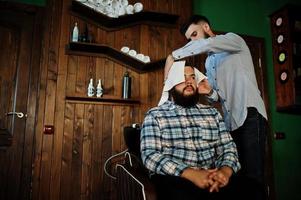 apuesto hombre barbudo en la barbería, peluquero en el trabajo. cabezal de lavado. foto