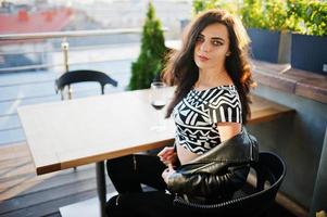 Young curly woman enjoying  her wine in a bar. photo