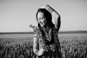 Tender indian girl in saree, with violet lips make up posed at field in sunset. Fashionable india model. photo