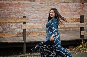 mujer india morena en vestido largo de moda bailando al aire libre. foto
