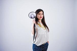 retrato de una mujer joven con pantalones azules y blusa blanca posando con megáfono en el estudio. foto