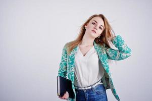 chica rubia con estilo en chaqueta y jeans con diario de cuaderno en las manos contra fondo blanco en el estudio. foto