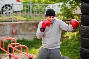 Man arabian boxer in hat training for a hard fight outdoor gym. photo