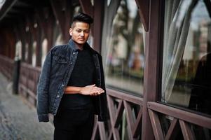 hombre indio guapo y de moda con chaqueta negra de jeans posada al aire libre. foto