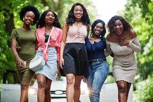 Group of five happy african american walking against white car. photo