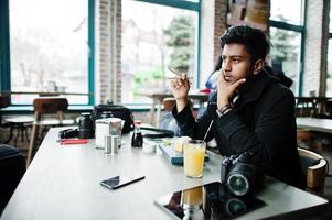 Casual and stylish young asian man with earphones at cafe eating sushi. photo