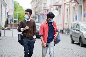 Coronavirus covid-19 concept. Two south asian indian man wearing mask for protect from corona virus walking at city. New normal lifestyle post pandemic in India. photo