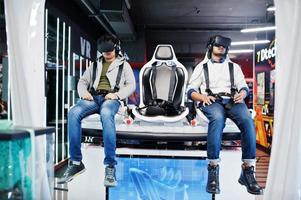 Two young indian people having fun with a new technology of a vr headset at virtual reality simulator. photo