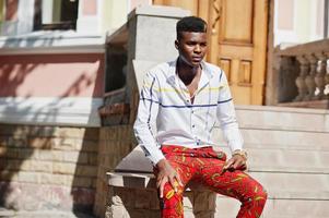 Portrait of handsome stylish african american model man in red throusers and white shirt. photo