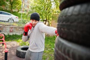 Man arabian boxer in hat training for a hard fight outdoor gym. photo