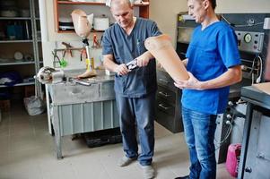 dos trabajadores protésicos que fabrican una pierna protésica mientras trabajan en el laboratorio. foto