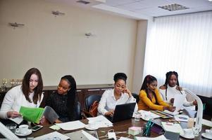 Multiracial women colleagues, crew of divercity female partners in office sit at the table. photo