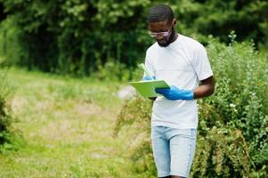 African volunteer man with clipboard in park. Africa volunteering, charity, people and ecology concept. photo