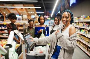 Group of african womans weighs apples in polyethylene bags at supermarket. photo