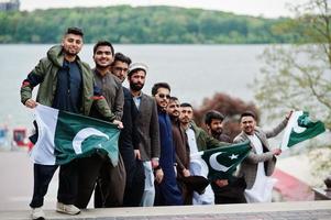 grupo de hombres paquistaníes vestidos con ropa tradicional salwar kameez o kurta con banderas de pakistán. foto