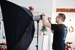 Photographer adjusts the flash light on studio. photo