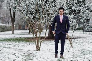 Elegant indian macho man model on suit and pink tie posed on winter day. photo