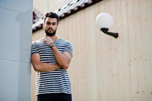 apuesto modelo de hombre de barba árabe alto en camisa despojada planteada al aire libre. chico árabe de moda. foto