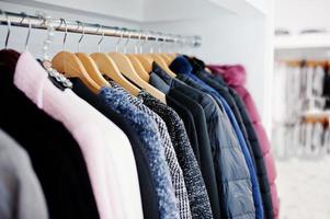 Close-up photo of fashionable clothes on hangers in the shop.