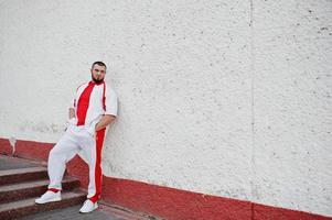 Young brutal bearded muscular man wear on white sport suit with red shirt. photo